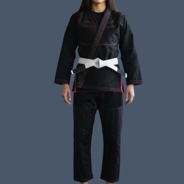JJB250_ female_model (1) Front view of female wearing a black BJJ gi with a pink trim.