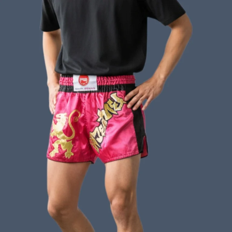 Person wearing raspberry red Muay Thai shorts with gold design.