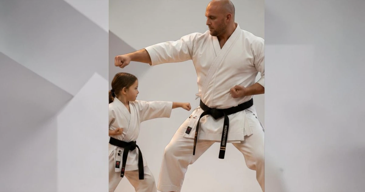 Image shows a large male student and a small junior student in karate uniforms
