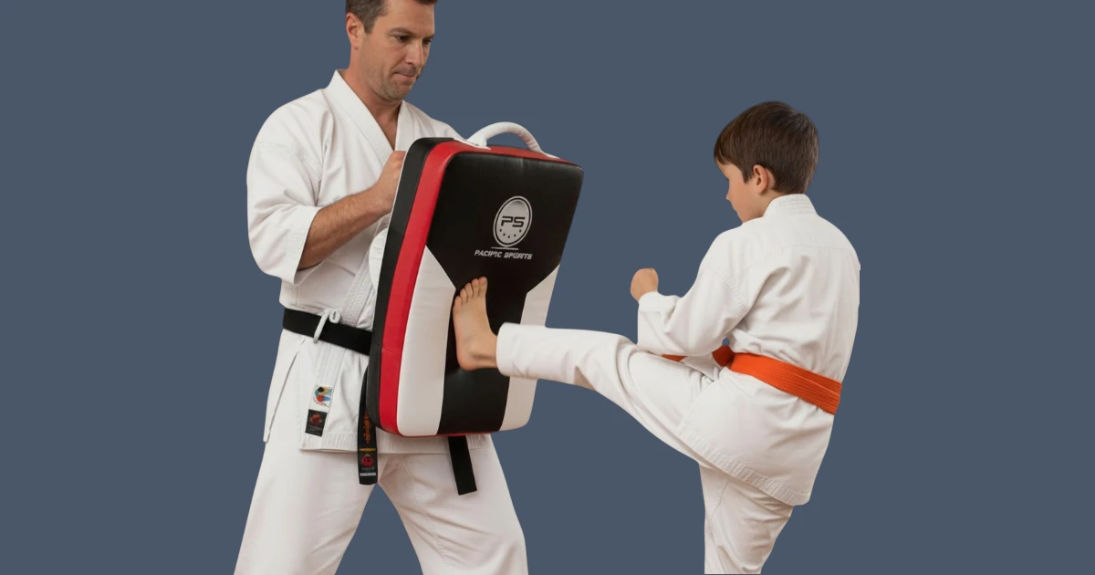 Image shows martial arts instructor holding large shield for student